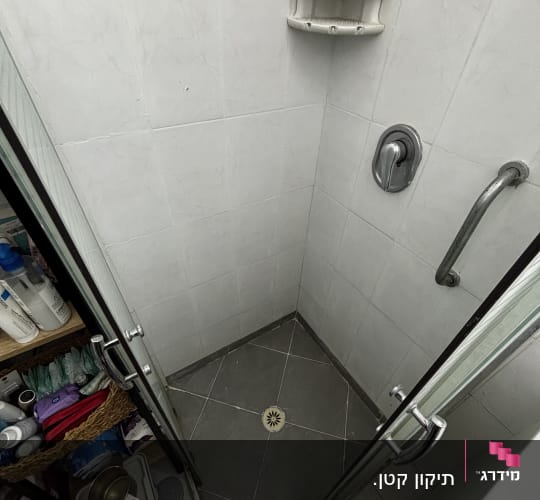 מקלחת עם דלת זכוכית ומדף קיר